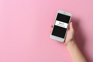 21 Mayıs mesajlı el ele tutuşan telefon. Pembe arka planda Ulusal MEMO Günü
