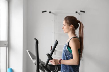Spor salonunda makine üzerinde sportif genç kadın eğitimi