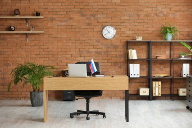 Modern dizüstü bilgisayarlı ve masada Rus bayrağı olan bir yargıçlık bürosu.