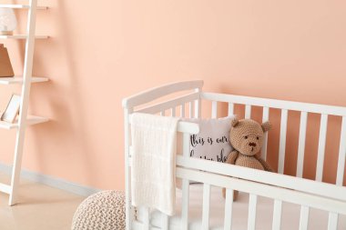 Modern çocukların odasındaki renkli duvarın yanında oyuncak ayılı beşik.