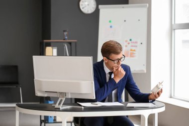 Ofisteki masada oturan beyaz alarmlı düşünceli genç iş adamı.