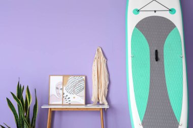 Sup sörf tahtası ve renkli duvarın yanındaki masa.