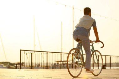 Şık bir genç adam sette bisiklet sürüyor.