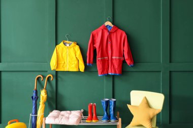 Koridorun içinde çocuk yağmurlukları, çizmeleri ve şemsiyeleri var.