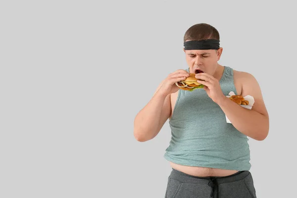 Túlsúlyos Ember Eszik Burger Könnyű Háttér — Stock Fotó