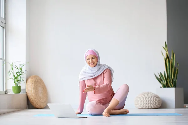 年轻的穆斯林孕妇在家用笔记本电脑练习瑜伽 — 图库照片