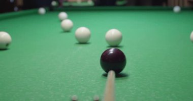 Oyuncu bilardo masasında topa vuruyor, yakın plan.