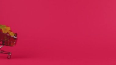 Kırmızı arka planda lezzetli jöle ayıları olan alışveriş arabasının devrilmesi