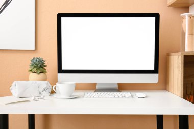 Renkli duvarın yanında modern bilgisayar, ev bitkisi ve fincanı olan işyeri