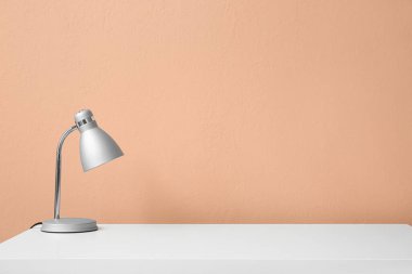 Renk duvarının yanındaki aydınlık masada modern lamba