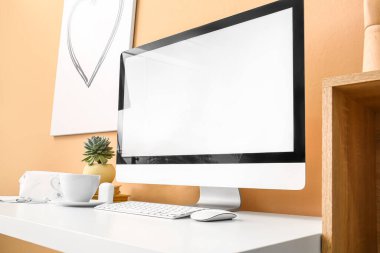 Renkli duvarın yanında modern bilgisayar ve fincanı olan işyeri