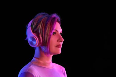 Sıradışı saçlı güzel bir kadın siyah arka planda müzik dinliyor.