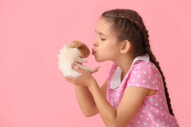 Pembe arka planda sevimli kobay faresi olan küçük bir kız.