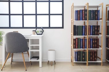 Ev kütüphanesinde kitapları olan şık bir iş yeri ve raf ünitesi