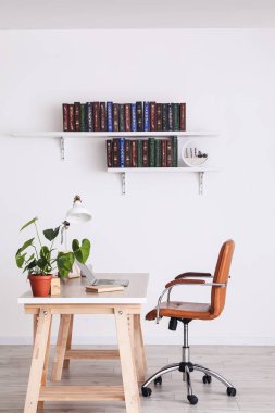 Masa ve raflardaki kitaplar odanın içinde duvarda asılı.