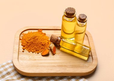 Bej arka planda yağ, zerdeçal kökü ve toz şişeleri