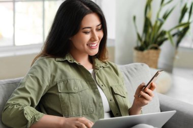 Cep telefonu ve dizüstü bilgisayarı olan güzel bir Asyalı kadın.