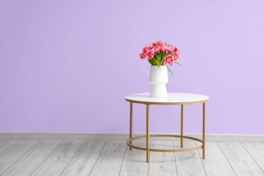 Odadaki renkli duvarın yanındaki masada laleli vazo.