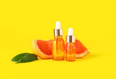 Sarı arka planda greyfurt yağı şişeleri