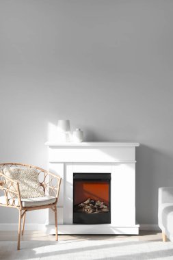 Hasır koltuk ve şömine. Vazolar ışık duvarının yanında.