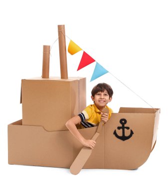 Küçük yakışıklı beyaz zemin üzerine karton gemi ile oynarken