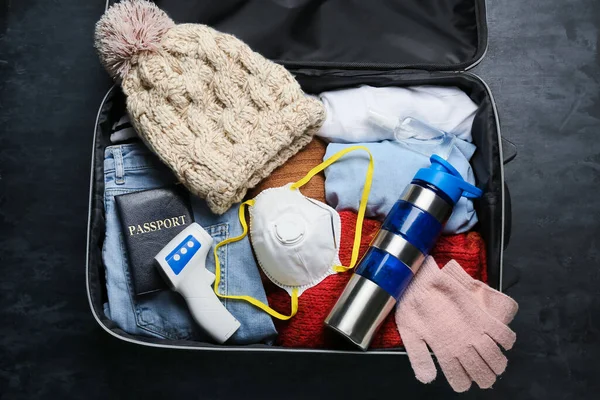 Koffer Met Stijlvolle Winterkleding Digitale Thermometer Medisch Masker Donkere Achtergrond — Stockfoto