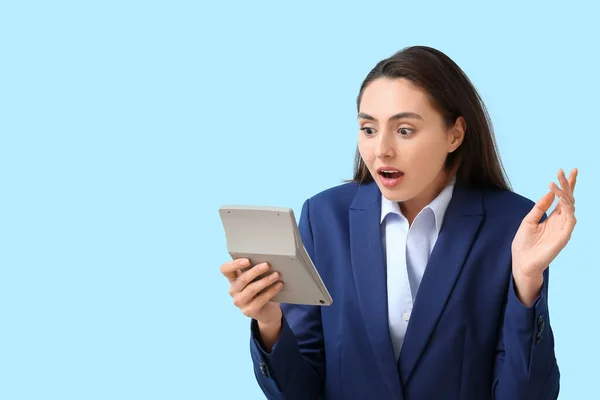 青い背景に電卓と衝撃的な若いビジネスマンの女性 — ストック写真
