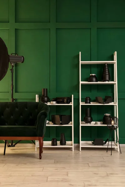 写真スタジオの緑の壁の近くにプロ仕様の機器とソファとシェルフユニット — ストック写真