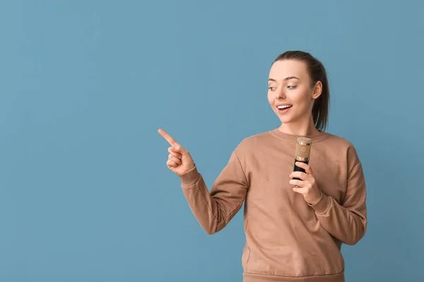 Młoda Kobieta Profesjonalnym Mikrofonem Wskazującym Coś Niebieskim Tle — Zdjęcie stockowe