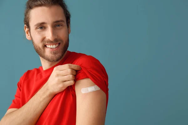 Young man with applied medical patch on color background