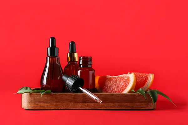 Houten Bord Met Flessen Grapefruit Etherische Olie Rode Ondergrond — Stockfoto