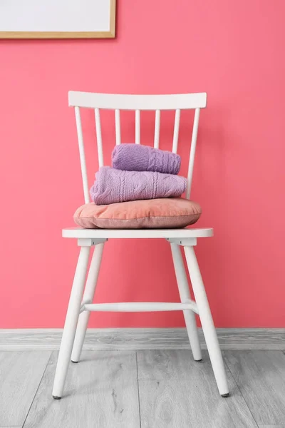 房间里靠近彩墙的椅子上堆放着一堆堆折叠的紫丁香毛衣 — 图库照片