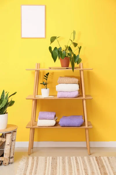 Shelving Unit Folded Sweaters Houseplants Yellow Wall — Stock Photo, Image