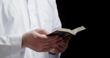 Müslüman adam siyah arka planda Kur 'an okuyor, yakın plan