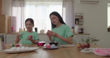 Anne ve küçük kızı mutfakta Paskalya için yumurta boyuyor.