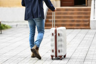 Dışarıda bavullu genç adam var.