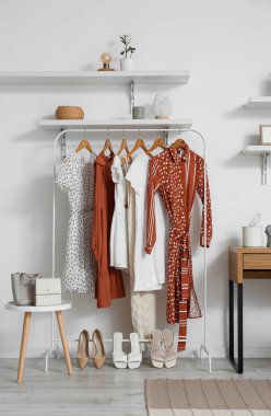 Odada şık kıyafetler ve ışıklı duvarın yanında ayakkabılar var.