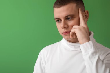 Endişeli genç adam yeşil arka planda, yakın plan