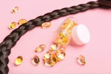 Pembe arka planda haplarla örülmüş saç teli.