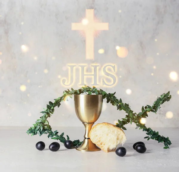 Chalice of wine with bread and fish made of branches on light background. Holy Communion concept