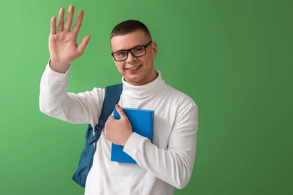 Männlicher Student Mit Büchern Wedelt Mit Der Hand Auf Grünem — Stockfoto