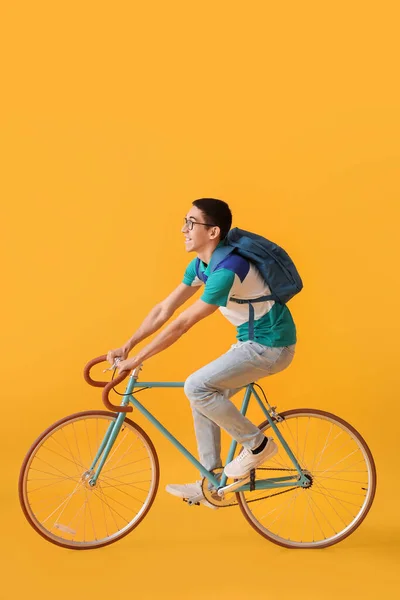Sarı Arka Planda Bisiklet Süren Asyalı Erkek Öğrenci — Stok fotoğraf