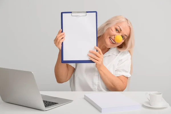 Funny Mature Woman Clown Nose Clipboard Table Light Background April — Stock Photo, Image
