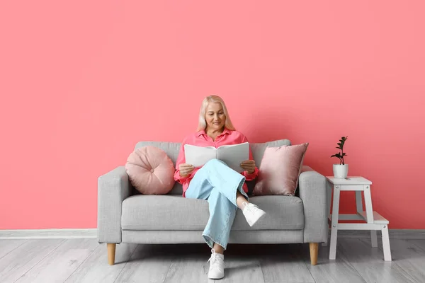 Mature Woman Reading Book While Sitting Sofa Pink Wall — Stock Photo, Image