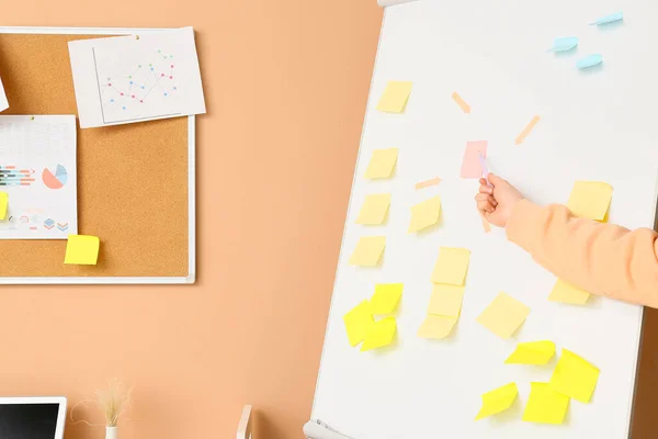 Frau Zeigt Auf Klebrigen Zettel Auf Flipchart Nahe Beiger Wand — Stockfoto