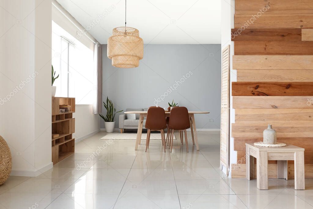 Interior of modern dining room with table, sofa and hanging lamp