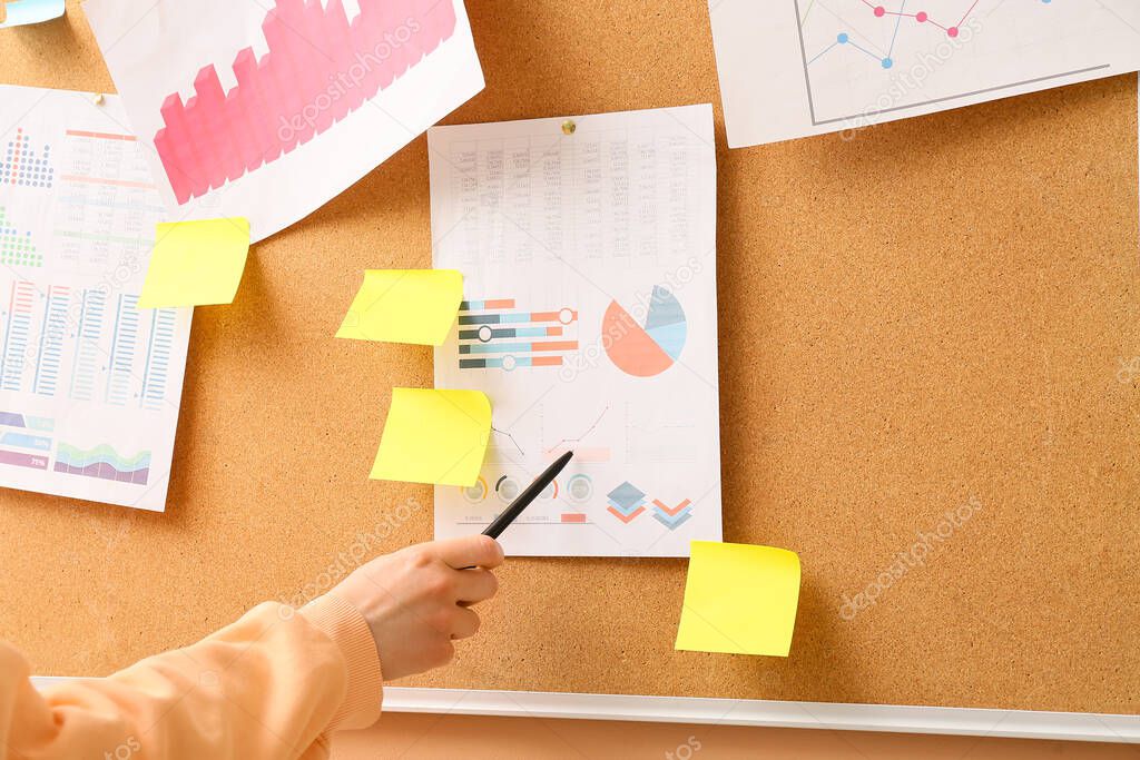 Woman pointing at charts on board with sticky notes