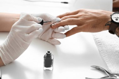 Manikür ustası erkek müşteriyle güzellik salonunda çalışıyor.