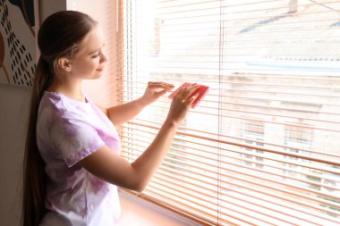 Evde pencere temizleyen genç bir kadın.