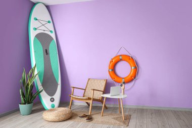 Koltuklu oda, masada modern dizüstü bilgisayar ve yemek sörfü tahtası.